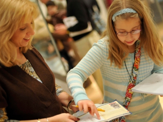 Kid pointing to activity book held by parent